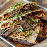 Close-up of a crispy brisket quesadilla filled with smoky brisket, melted cheese, diced onions, and fresh cilantro on a serving tray.